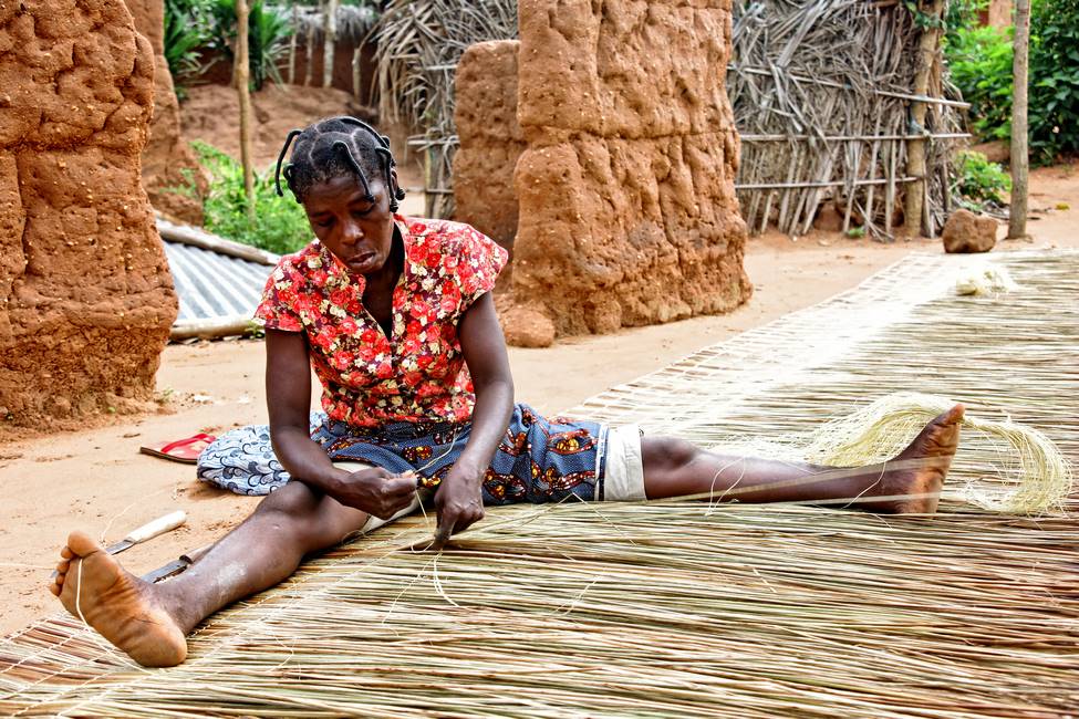 Voyage Bénin - Femme vannière tressant une natte dans un village au Bénin